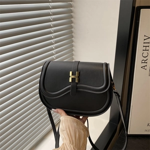 Minimalist black leather saddle bag with gold H clasp shown from a front angle