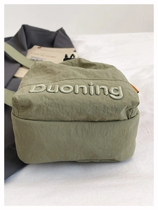 Macro shot of olive green nylon crossbody bag showing detailed duoning letter embroidery