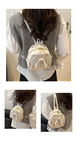 Détail du mini sac à dos beige avec imprimés lapins, fraises et un nœud blanc élégant