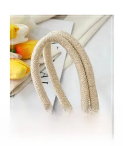 Detail of the woven beige cotton rope handle on a stylish minimalist bucket bag