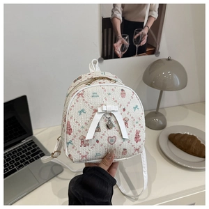 Détail du sac à dos blanc avec imprimé fleurs et ours et pendentif en cœur