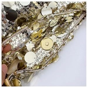 Detailed close-up of golden sequins and magnetic clasp on a luxury chain bag