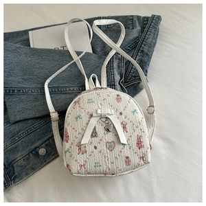 Close-up of cute white mini backpack with pink rabbit prints and heart pendant