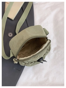 Top view of open green nylon crossbody bag showing spacious interior and zipper detail