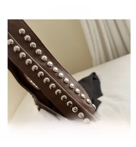 Detail shot of brown leather shoulder bag featuring vintage silver double-row metal rivets