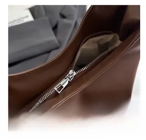 Detailed macro view of a smooth silver metal zipper on a brown leather tote bag
