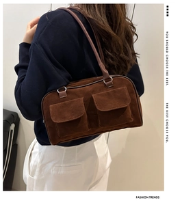 Détail du sac à bandoulière en daim marron avec deux poches à rabat et design rétro chic