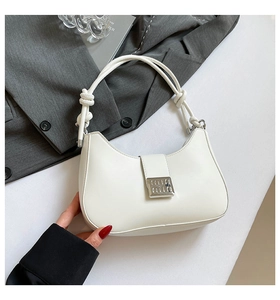 Close-up of a white leather hobo bag with a silver square buckle and knotted strap detail