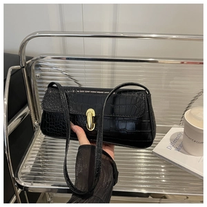 Detail of black crocodile embossed faux leather underarm bag with gold metal buckle