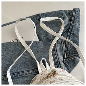 Close-up of white mini backpack with floral bear prints and gold zippers