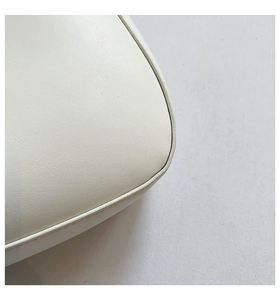 Detail shot of white leather texture and premium piping craftsmanship on handbag corner