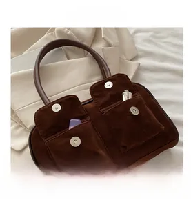 Detail of dark brown suede shoulder bag with dual magnetic flip pockets and leather handle