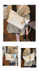 Detail of a creamy beige glossy leather tote bag featuring a decorative sports charm