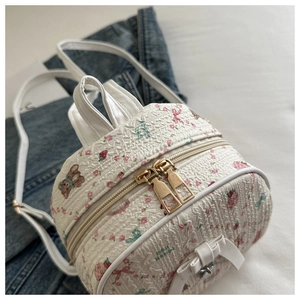 Detailed macro view of cute floral bear print on white textured mini backpack fabric