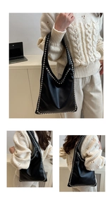 Close-up of black oil wax leather tote bag featuring silver rivet trim and roomy interior