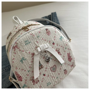 Close-up of white mini backpack with pink bear prints and silver heart pendant