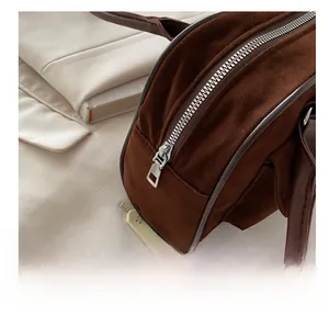 Detail view of smooth silver zipper on dark brown suede handbag with leather trim