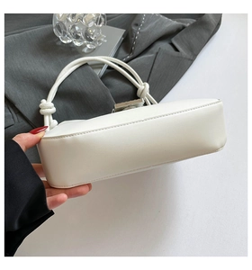 Detail of white square handbag showing knot handle, silver buckle, and premium stitching
