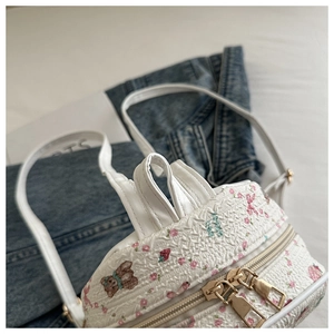 Detailed view of the woven white backpack featuring cute bear and floral prints