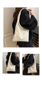 Detailed view of white faux leather tote bag with silver studs on the shoulder strap