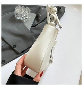 Detail of minimalist cream leather shoulder bag with knot decoration and metal ring