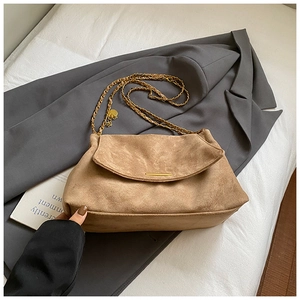 Detailed close-up of brown suede crossbody bag with gold chain strap on grey blazer