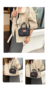 Outdoor street shot of grey denim crossbody bag with contrast stitching and leather tag