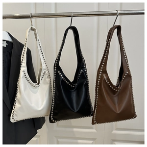 Detailed view of铆钉 soft leather tote bags in white black and brown hanging on a rack
