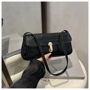 Detail of black crocodile texture handbag with gold oval clasp and sleek leather strap