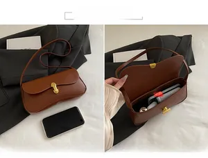 Detail view of brown baguette bag with gold buckle showing interior capacity for phone