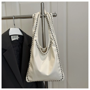 Close-up of white PU leather hobo bag with silver rivet studs hanging on a hanger