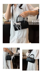 Detail of black Boston bag with pearl lace bow, showing handheld and crossbody styles