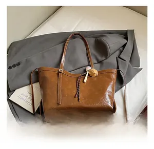 Detailed texture of brown oil wax leather tote bag with baseball glove pendant