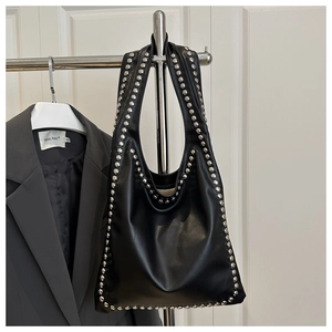 Detail of black matte leather tote bag with silver studs hanging on a metal hanger