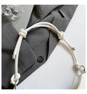 Detail of white leather shoulder bag featuring unique double knotted straps and silver metal tips