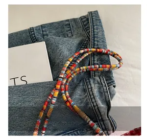 Detail shot of colorful handcrafted beaded strap on blue denim and white background