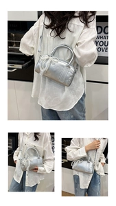 Detail of silver metallic handbag with pearl lace bow charm and brand embossing