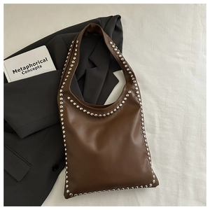 Detail view of vintage brown shoulder bag featuring polished silver round stud decorations