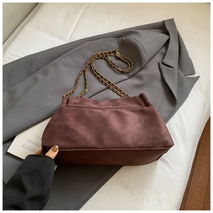 Close-up of burgundy suede tote bag with elegant gold chain strap on grey blazer
