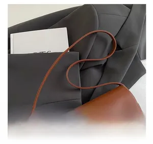 Detail of a brown leather shoulder bag featuring a polished gold rectangular metal buckle