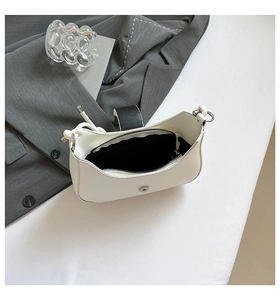 Interior detail of white shoulder bag showing black lining, zip pocket, and magnetic clasp