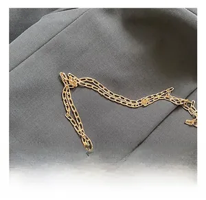 Detail of high-quality gold hardware with pearl charms on a grey textured fabric background