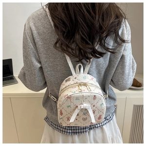 Détail d'un mini sac à dos beige à motif floral, ours et nœud en ruban blanc élégant