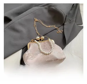 Detail of light pink floral jacquard bag with vintage gold frame clasp and pearl handle