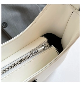 Detail of silver metal zipper closure on solid color faux leather handbag with black lining