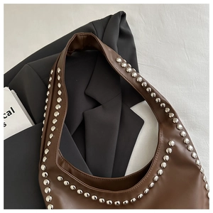 Close-up of brown matte leather bag featuring silver rounded stud rivets and punk style