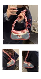Close-up of denim shoulder bag with red gingham ruffles and embroidered apple patch detail
