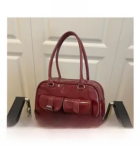 Detail shot of a dark red patent leather bowling bag featuring dual buckled front pockets