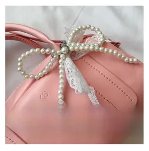 Detail of pink PU leather Boston bag with pearl bow and white lace trim accents