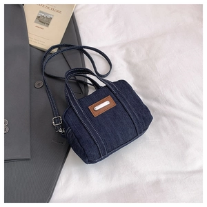Close-up of dark blue denim mini bag with contrast stitching and leather patch detail
